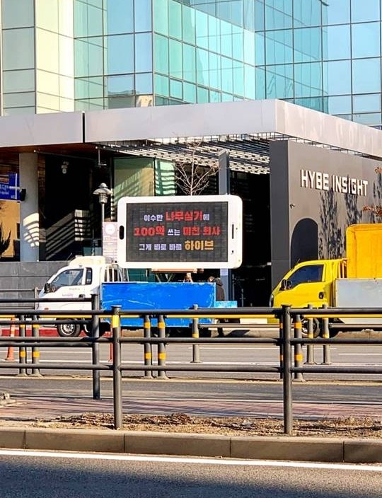 Фанаты SM Entertainment отправили грузовики с фразами протеста к зданию HYBE
