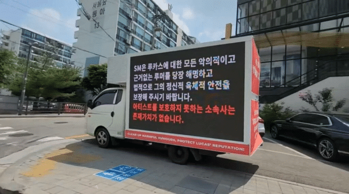 Международные фанаты отправляют грузовики протеста к зданию SM, требуя защиты для Лукаса