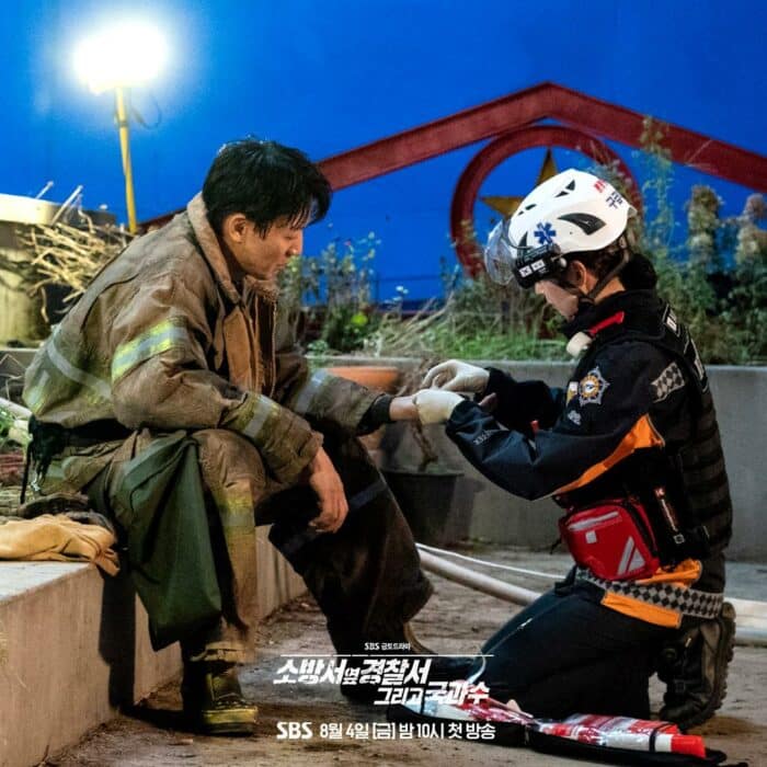 Ким Рэ Вон улыбается Гон Сын Ён, которая обрабатывает его раны, во 2 сезоне дорамы «Полицейский участок рядом с пожарной частью»